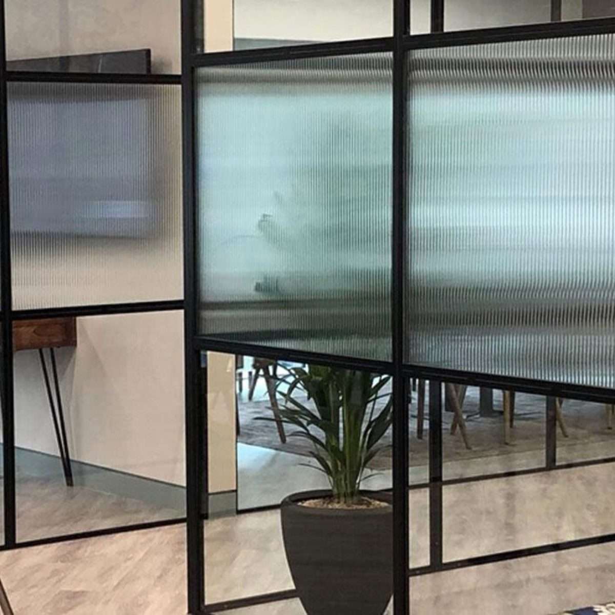 Reeded window film applied to interior glass partitions, creating a translucent effect with vertical textured lines for stylish privacy