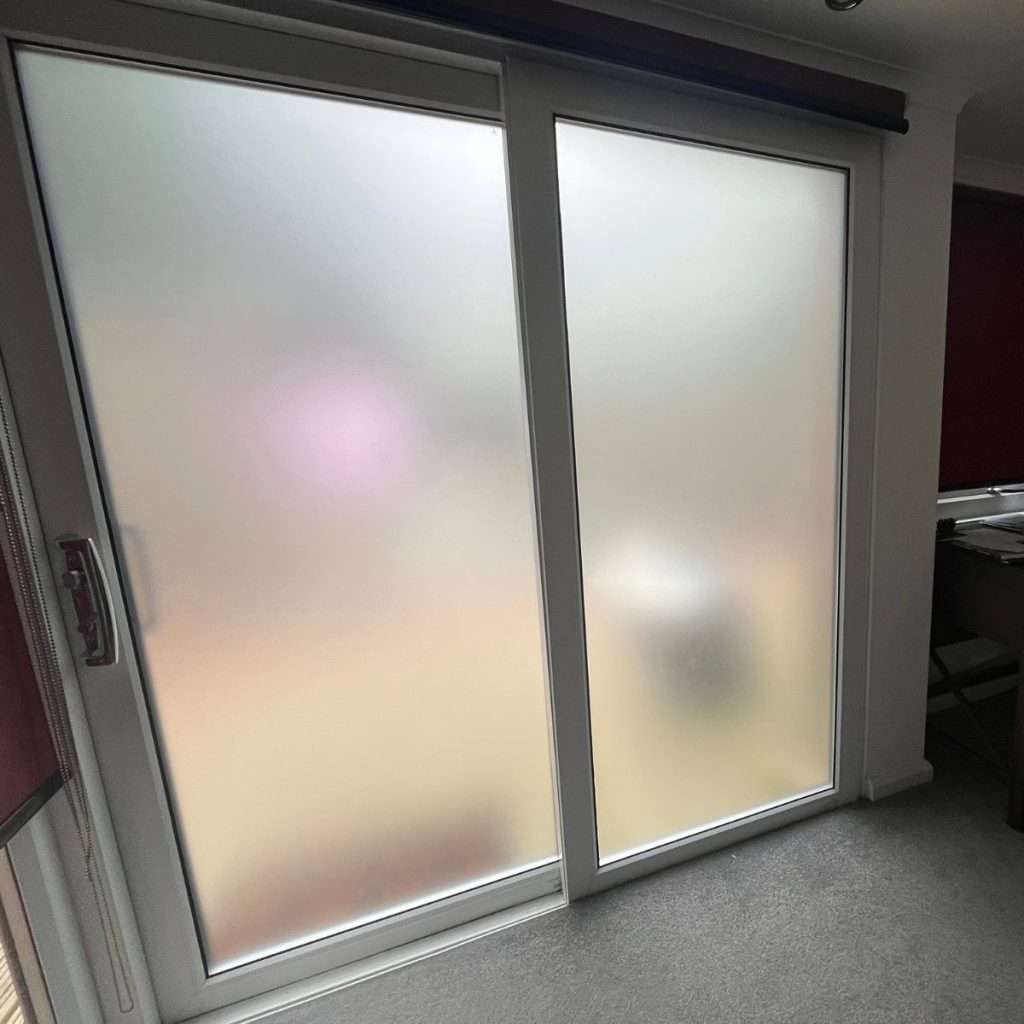 “Frosted window film applied to sliding door panes in a clinic, providing full privacy without making the room dark