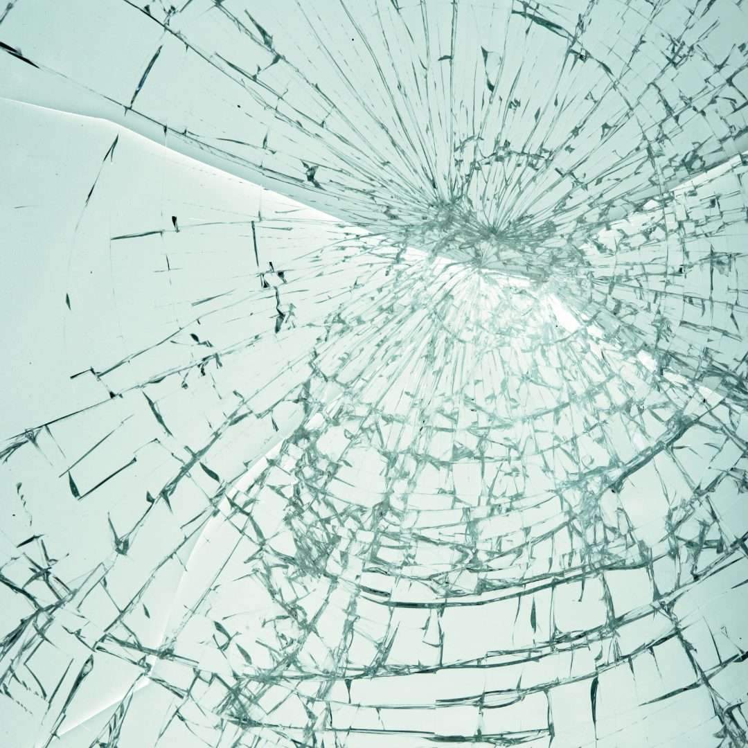 Shattered glass spiderweb pattern after high-impact, illustrating how bomb blast security film holds broken glass together for improved safety