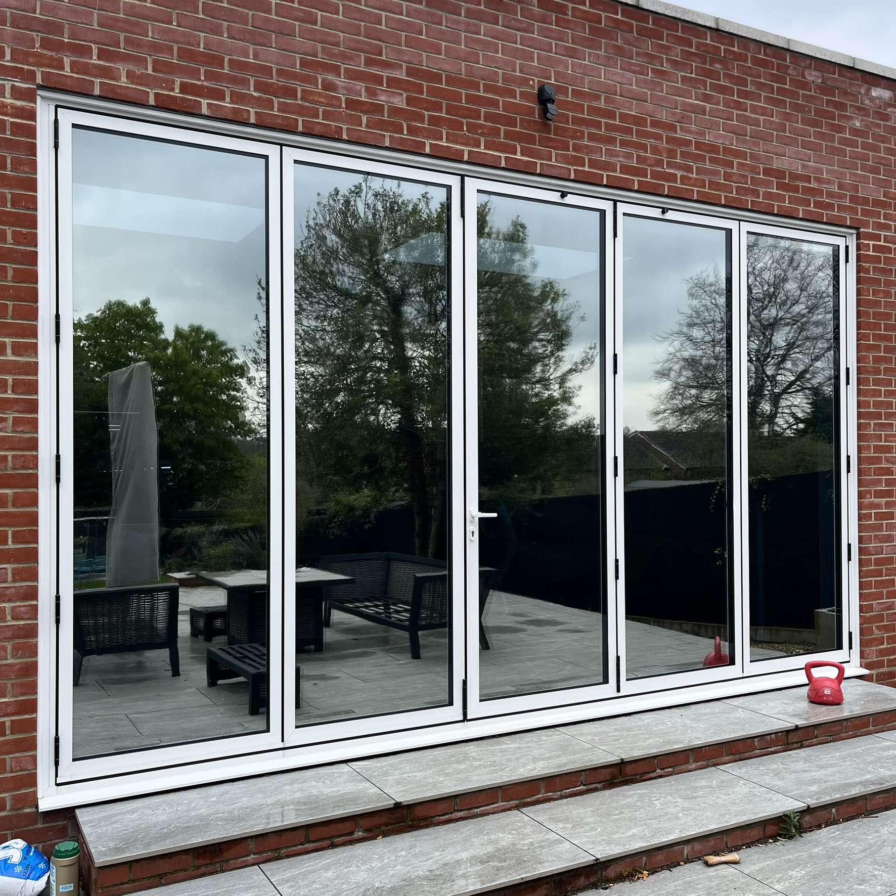 External view of a residential property in Suffolk showing Silver 20 reflective solar window film applied to bifold doors, enhancing privacy while providing effective solar heat control.