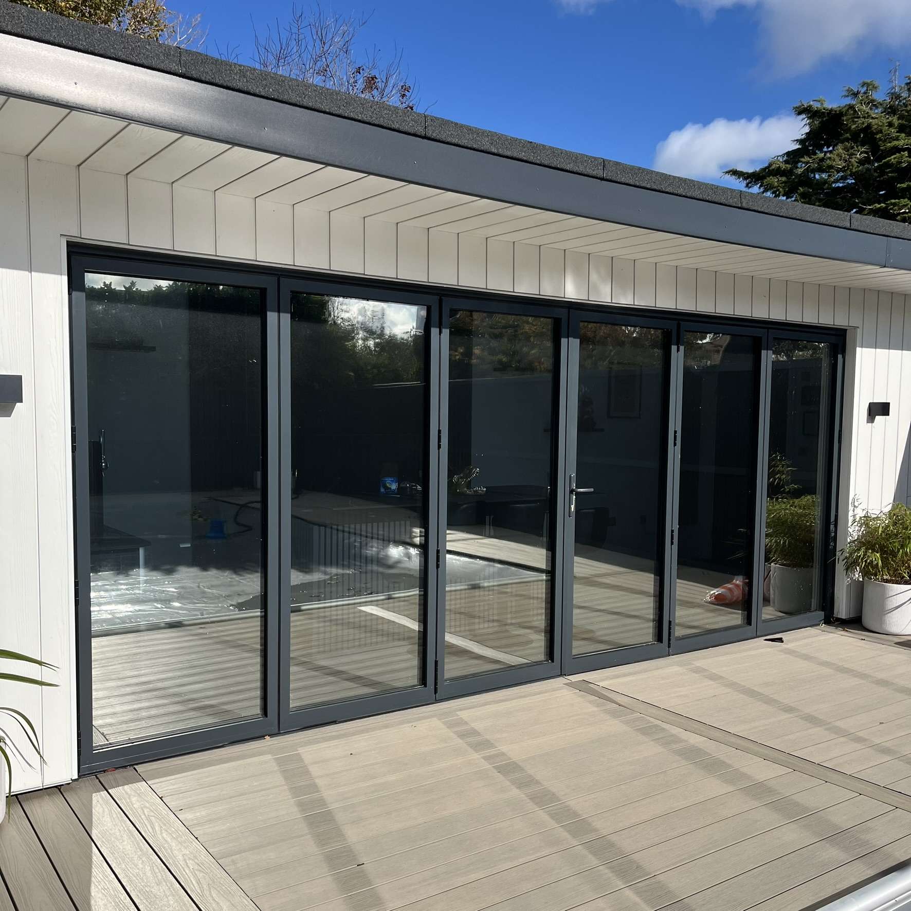 External view of an outbuilding in Portsmouth with bifold doors fitted with Silver 35 reflective solar window film, helping control heat while adding privacy.