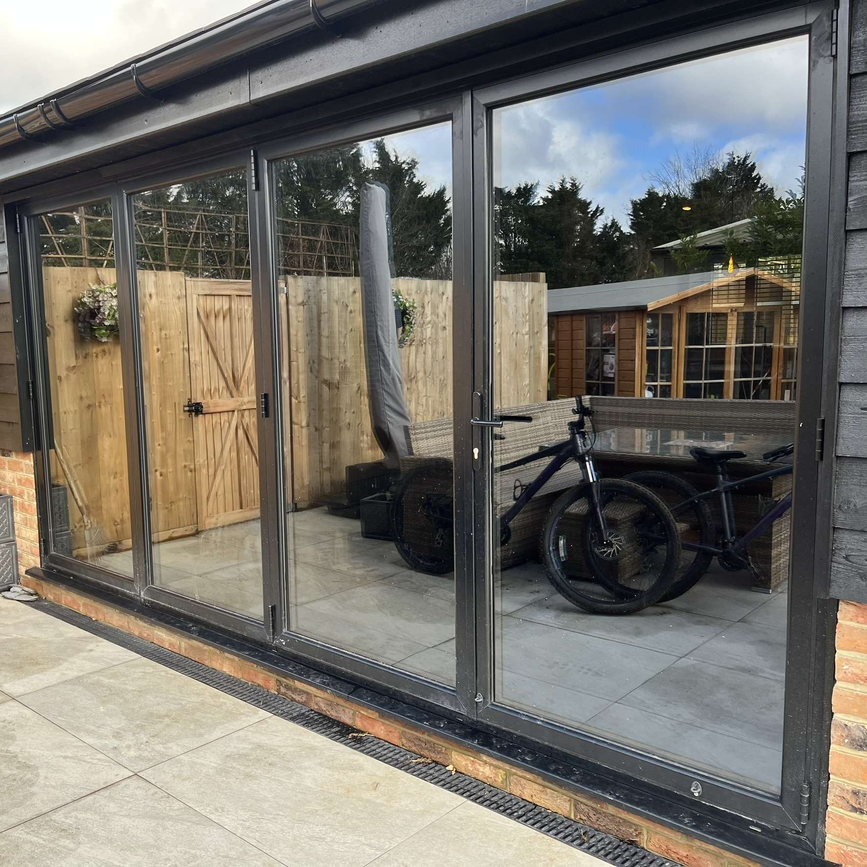External view of barn bifold doors in Ongar fitted with Slate 20 tinted solar window film, improving privacy with a modern look while reducing glare.