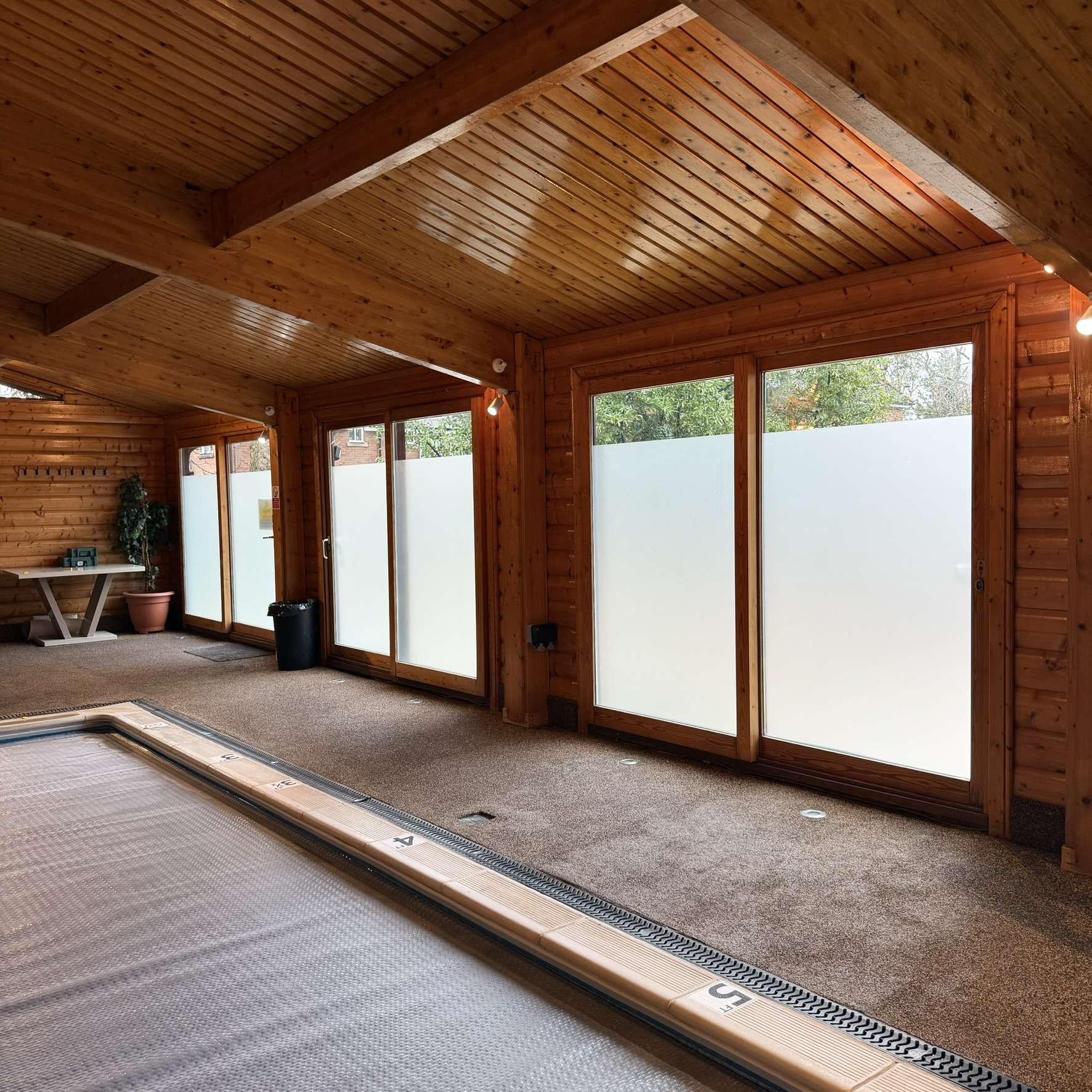 Internal view of a cabin in High Wycombe showing a frosted window film band applied to the glazing, providing privacy for pool use while allowing natural light above the film.