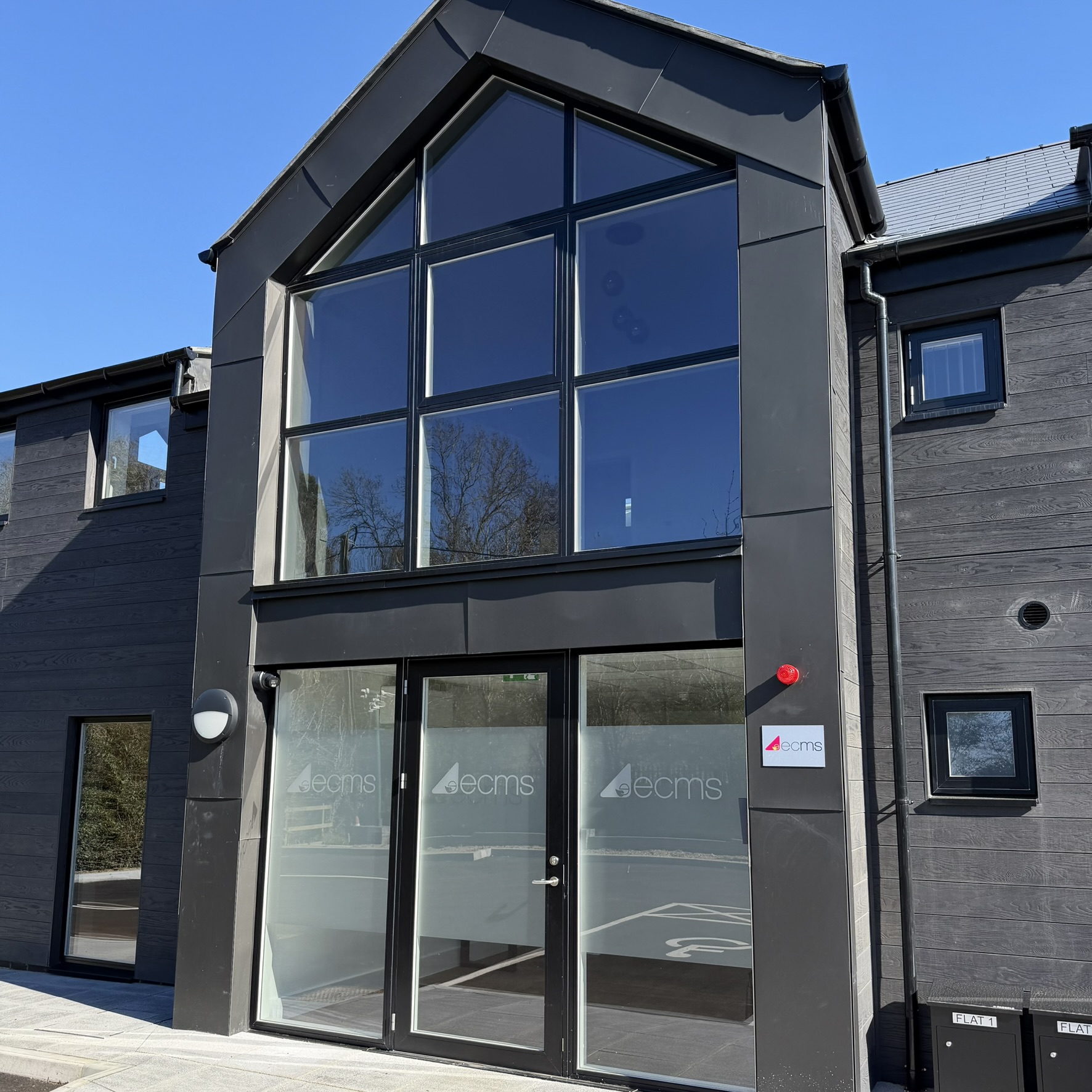 Angled external close-up of an office building in Sevenoaks with Slate 35 tinted solar window film applied, supporting a more comfortable working environment through glare reduction and heat control.
