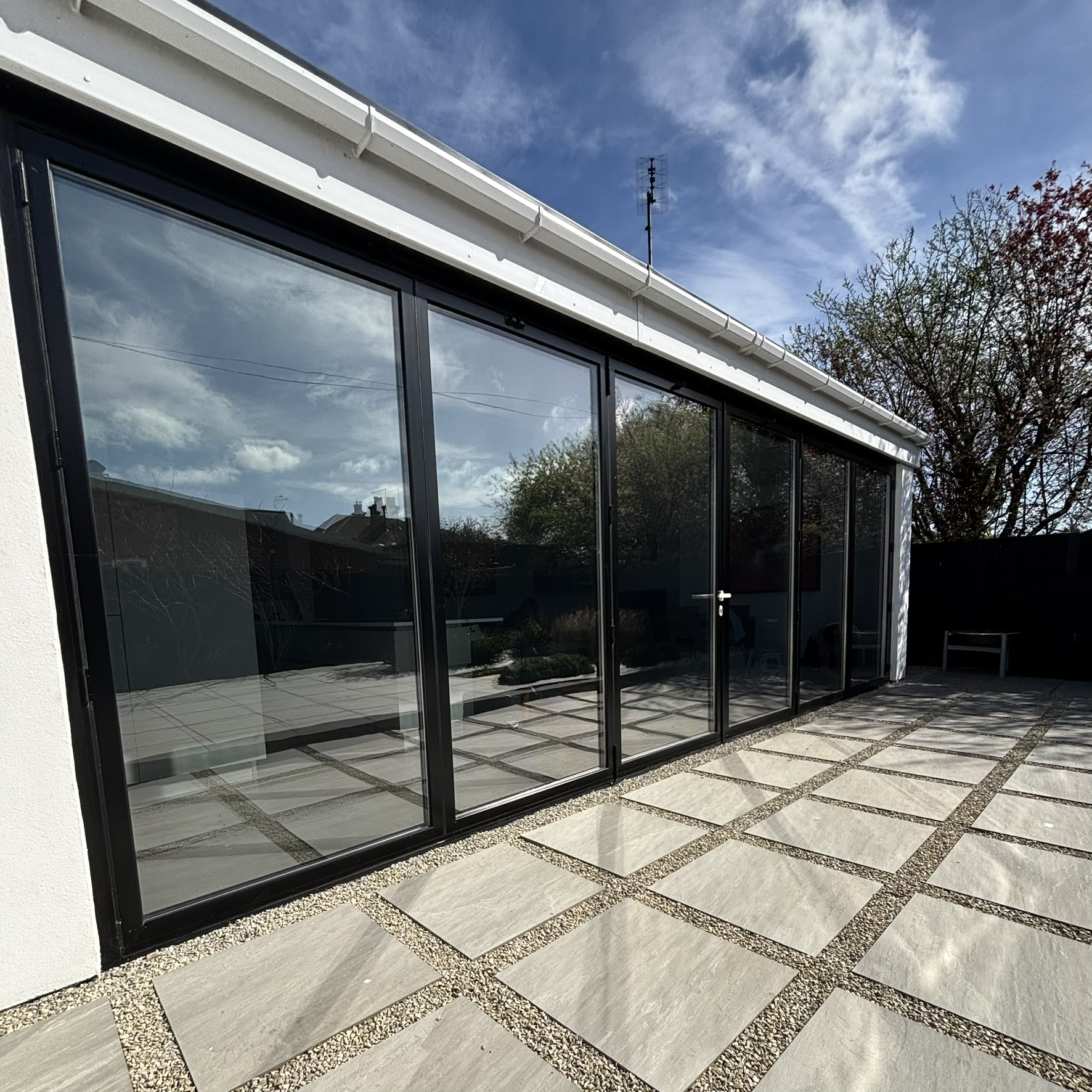 External view of bifold doors in Canterbury fitted with Silver 50 reflective solar window film, creating a subtle, uniform glass appearance while offering year-round heat and UV control.