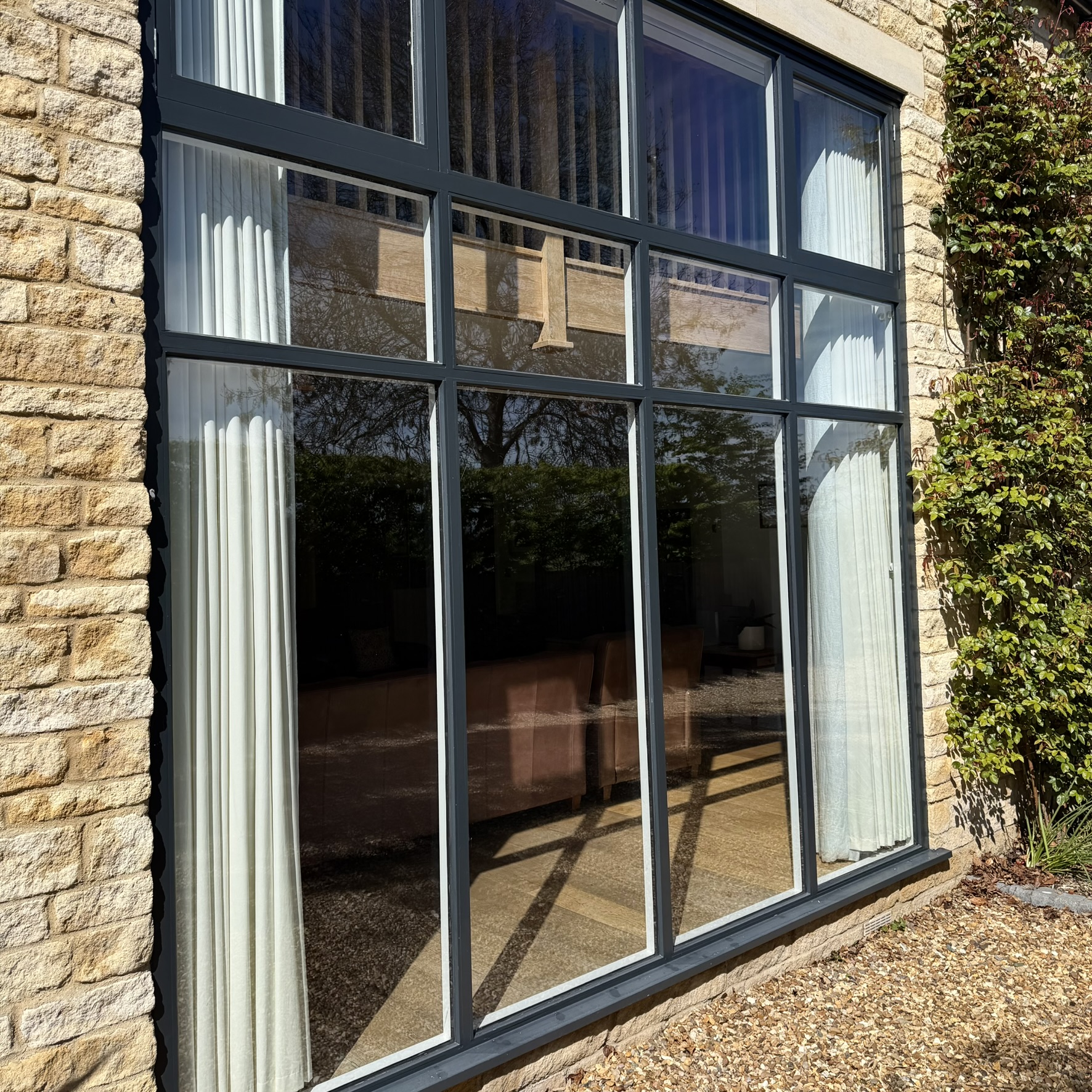 External view of a large glazed section on a residential property in Nassington, with doors and upper panes fitted with specialist clear UV window film to help protect interiors from sun damage while maintaining a clear appearance.