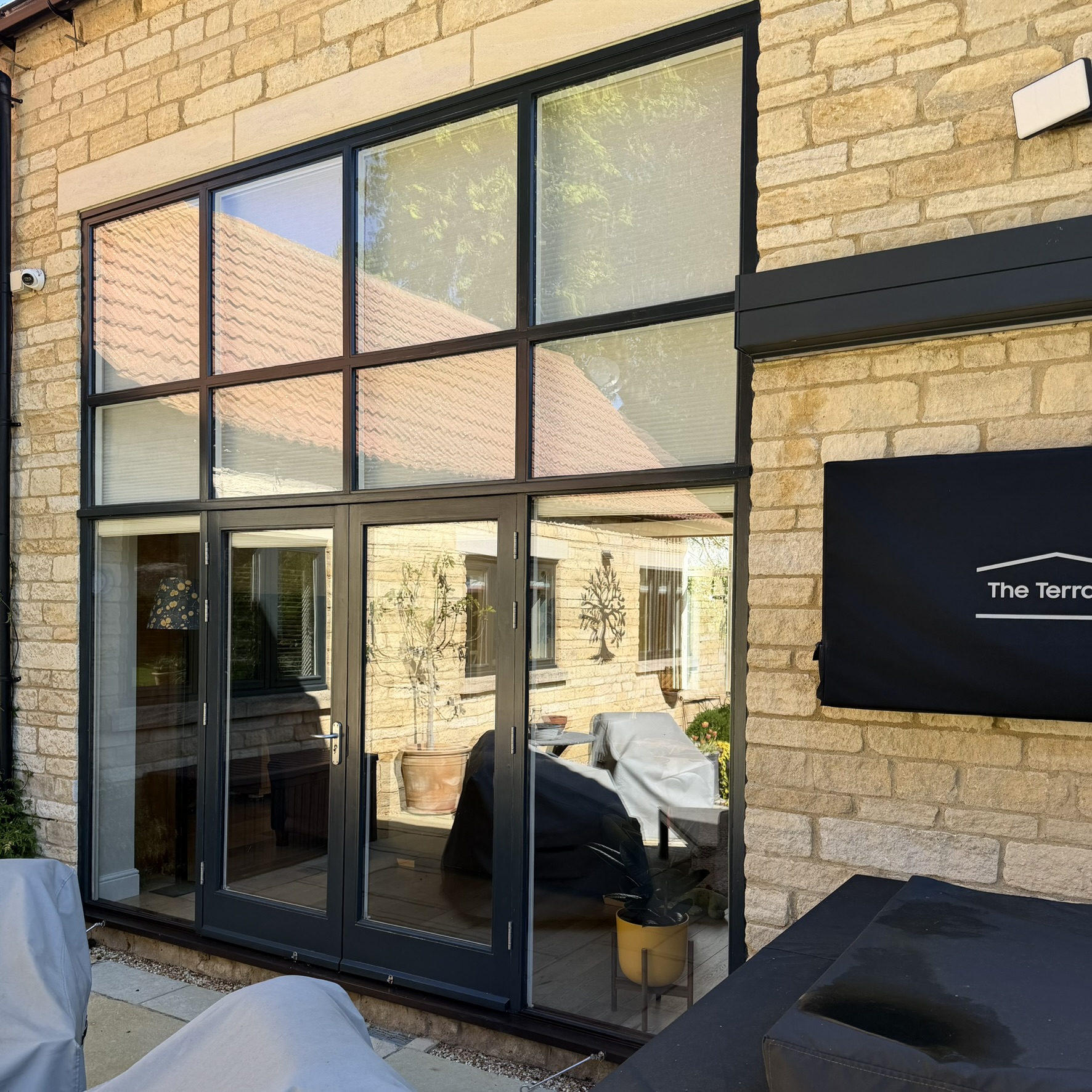 External view of full-height glazing on a Nassington property, including doors and multiple upper panes fitted with specialist clear UV window film, reducing UV exposure while preserving the natural look of the glass.