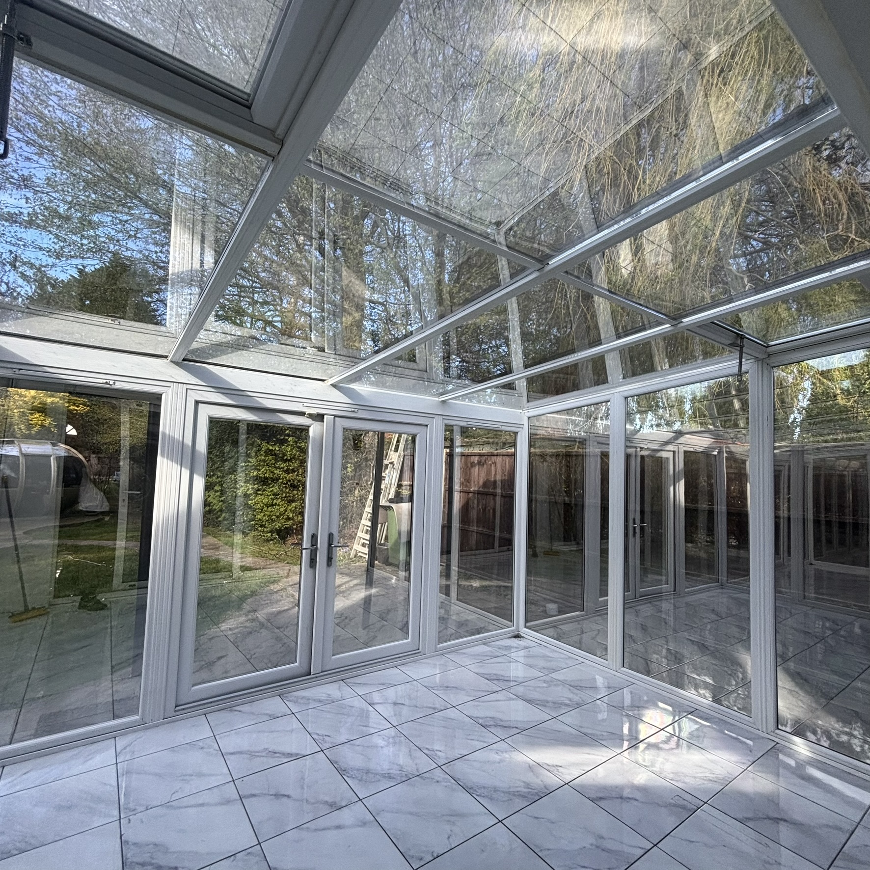 Internal view of a large conservatory in North London fitted with Silver 20 reflective solar window film across the side glazing and roof panes, providing strong solar protection to improve comfort and efficiency.