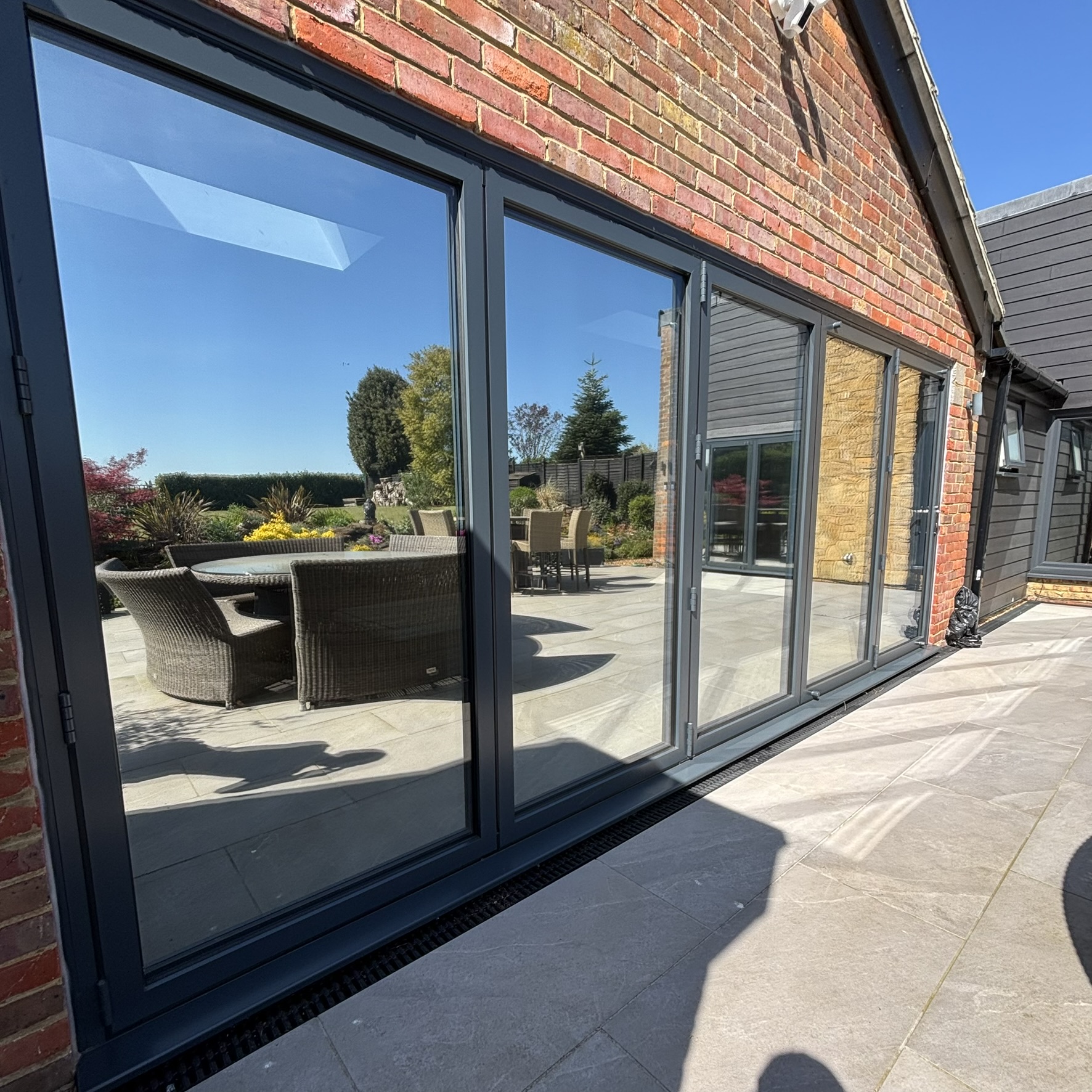 External view of bifold doors in Brickhill fitted with Silver 20 reflective solar window film, improving the appearance of the glass while adding privacy and UV protection for interior furnishings.