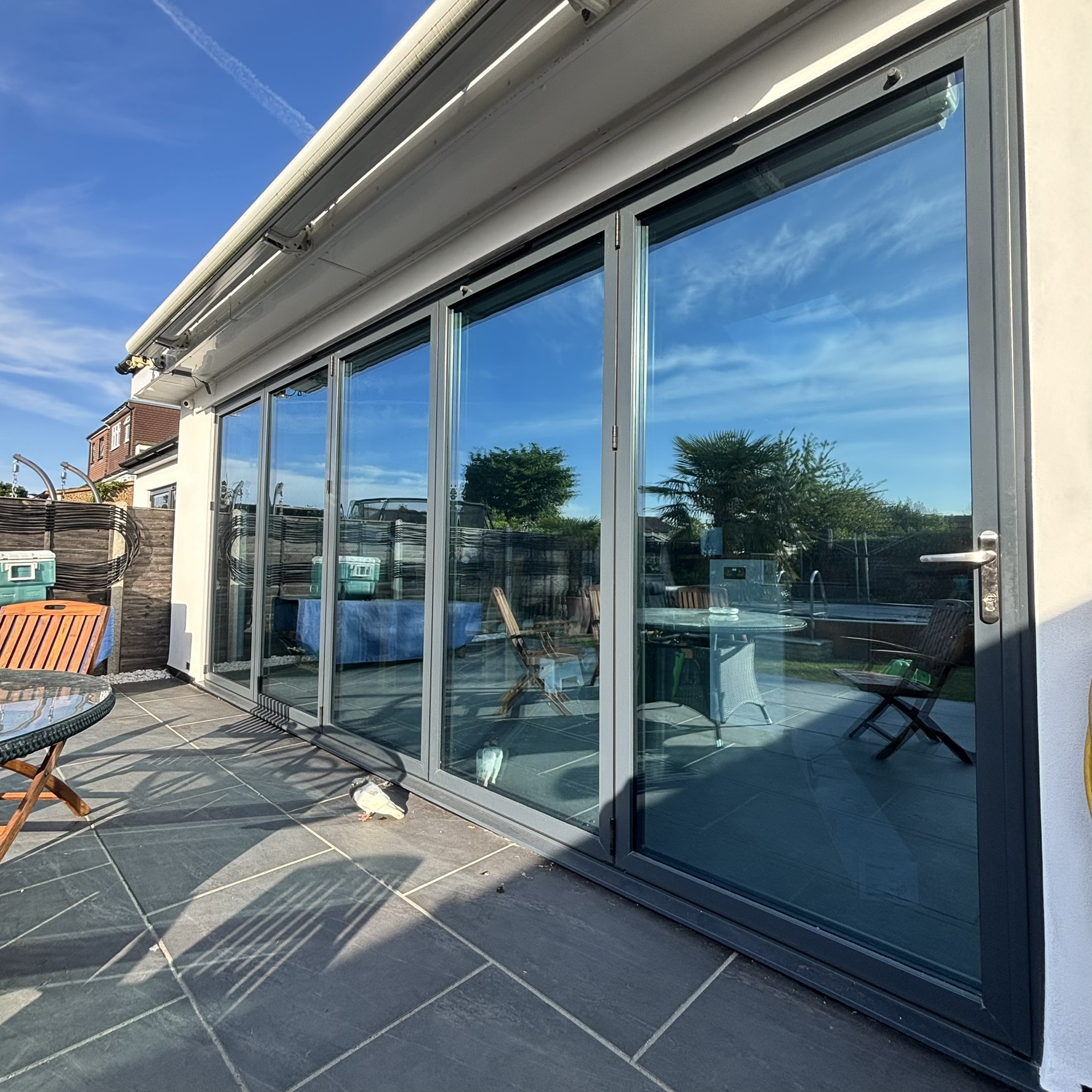 External view of bifold doors in Epsom, Surrey, fitted with Silver 20 reflective solar window film for a sleek appearance, daytime privacy, and year-round solar control.