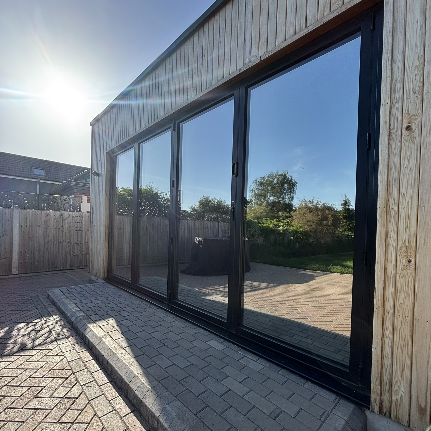 External view of bifold doors on a residential cabin in Wickford, Essex, fitted with Silver 20 reflective solar window film for privacy from neighbours and UV protection for decorated interiors.